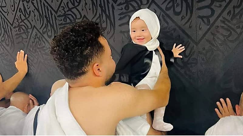 صورة مؤثرة لطفلة رضيعة تبتسم لوالدها أثناء لمسها الكعبة