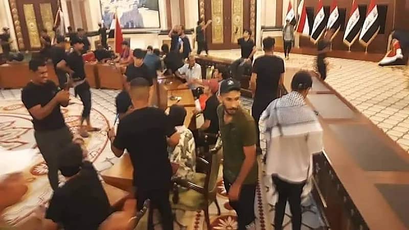 شاهد.. متظاهرون يقتحمون غرفة نوم الرئيس العراقي ويستولون على بدلته