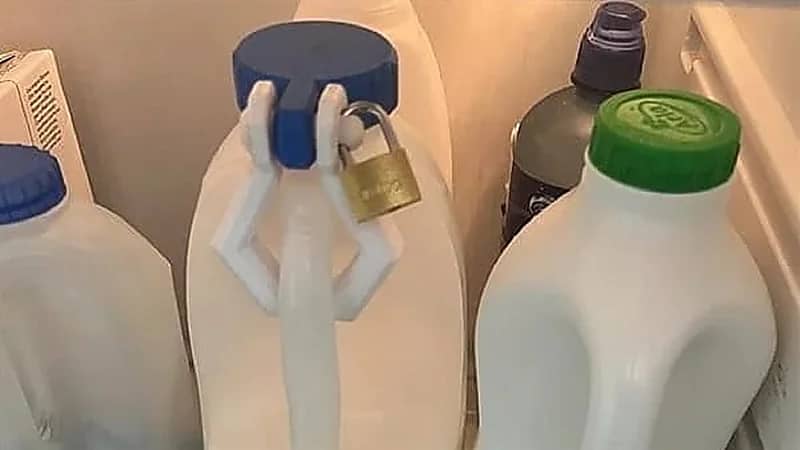 رجل يغلق زجاجة حليب بـ قفل في محل عمله